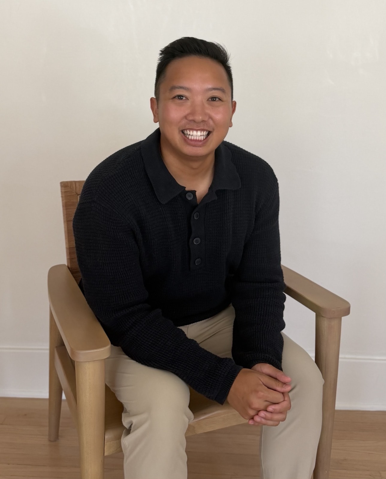 Dr. Binh Pham, seated in a wooden chair, smiling